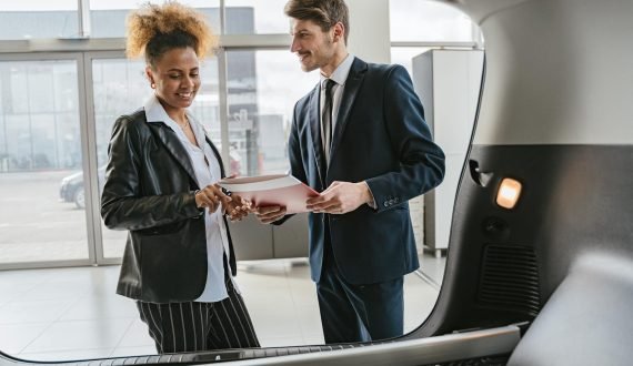 Dealer discussing vehicle options with a client inside a modern car showroom.